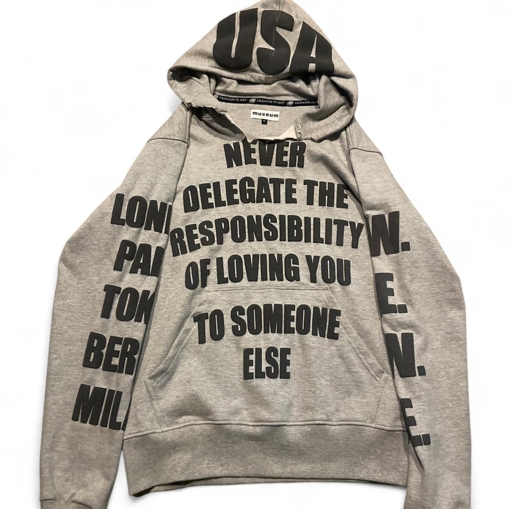 Museum Clothing gray hoodie with black text reading 'NEVER DELEGATE